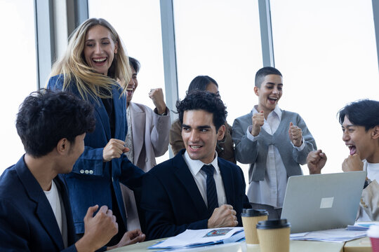 Happy diverse business team cheering with excitement in modern office celebrating corporate success meeting project goal together today
