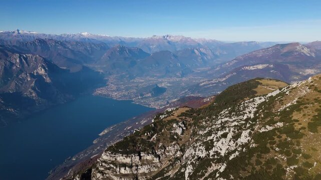 Cinematic aerial shot overlooking Lake Garda and the surrounding Italian Alps from the summit of Monte Altissimo. Ideal for travel documentaries, wellness retreats, and sustainability themes