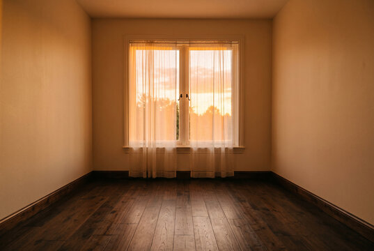Minimalist empty room with wooden floor and golden sunset light