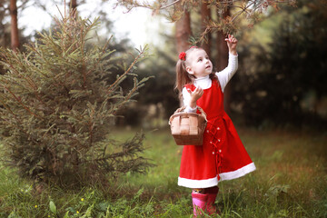 Obraz premium A little girl in a red hat and dresses is walking in the park. Cosplay for the fairytale hero 