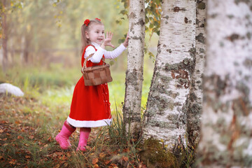 Obraz premium A little girl in a red hat and dresses is walking in the park. Cosplay for the fairytale hero 