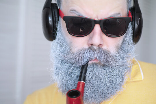 Guy smoking tobacco pipe. Hipster with grey beard and mustache. Bad habits conce