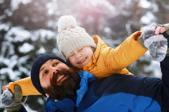 Happy family playing and laughing in winter outdoors in the snow. City park winter day.