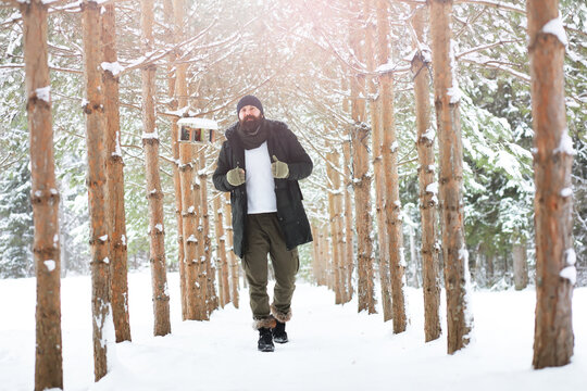 Outdoor portrait of handsome man in coat and scurf. Bearded man in the winter woods.