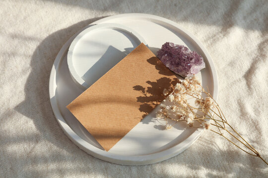 Esoteric practices. Craft business card and amethyst druse in a tray on a textile background with natural sunlight.