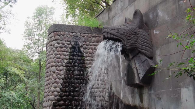 Prehispanic fountain aztec figures ancient sculpture broad daylight clean water green trees surrounding