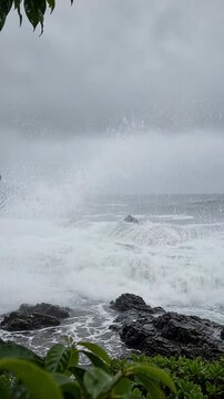 Gloomy Seascape With Turbulent Waves Crashing Against Rocky Shoreline Under Overcast Skies