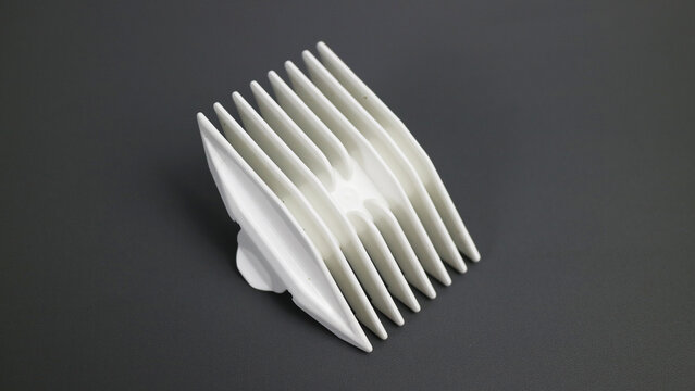 White hair clipper comb attachment on grey surface