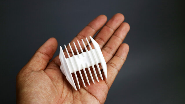 White plastic hair clipper guard attachment on hand