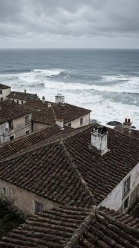 Overcast Coastal Landscape with Traditional Rooftops Overlooking Turbulent Ocean Waves
