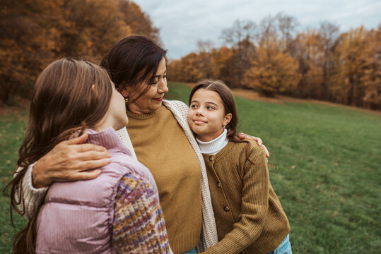 Grandmother spending time with granddaugters, walking in autumn nature.