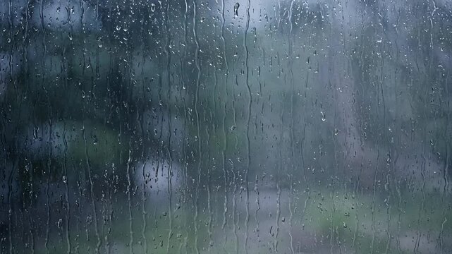 Raindrops on Window Glass with Blurred Natural Landscape Background in Overcast Weather