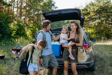 Obraz premium Family unloading luggage from car and setting up a campsite.