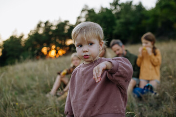 Obraz premium Young child spending summer evening with family in nature.