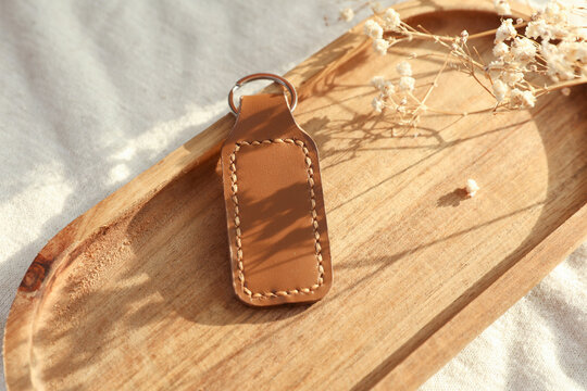 Brown leather keychain in tray on fabric background with natural sunlight