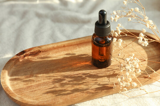 Serum glass bottle in tray on fabric background with natural sunlight