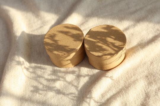 Craft round boxes on fabric background with natural sunlight. Beauty concept