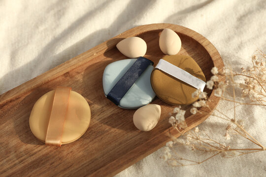 Set of makeup sponges in tray on fabric background with natural sunlight. Business concept