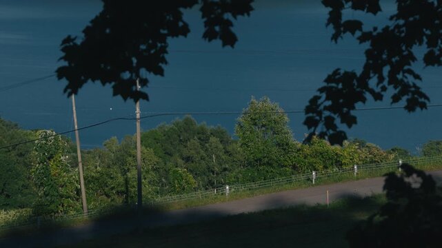 Downhill Road with Utility Pole Overlooking Lake from Mountain Shadow
