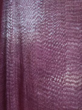Close-up of purple fabric texture. The weave is visible and thin.