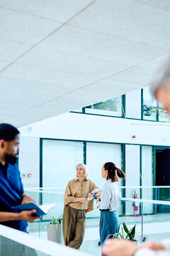 Diverse business professionals communicating and collaborating in a bright, contemporary office building atrium, fostering teamwork