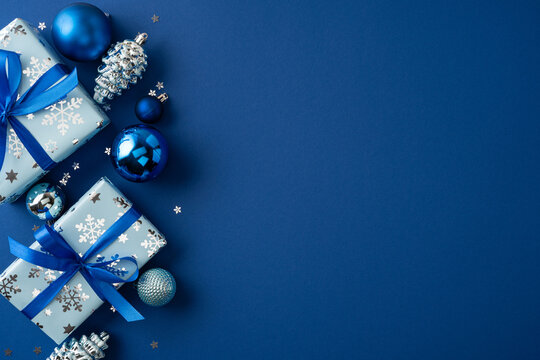 Merry Christmas and Happy New Year blue holiday gifts with ribbons and ornaments on navy background with lot of blank space for promo