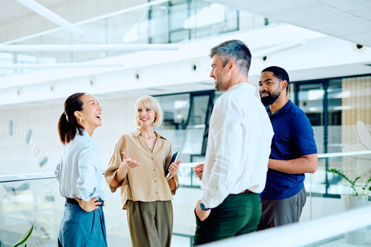 Diverse business professionals having a casual discussion and laughing together during a break in a modern office environment