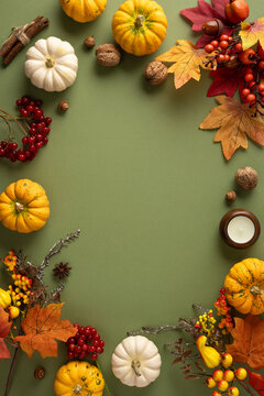 Autumn thanksgiving arrangement with pumpkin, colorful leaf and rustic harvest accents on vertical soft green table with empty space