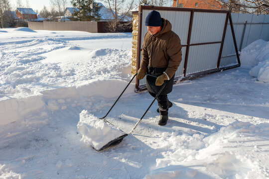 Man shovels snow in snowy yard