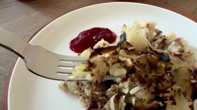 Eating Cabbage Casserole With Lingonberry Jam From a Plate