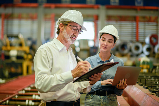 Owner boss manager assistant secretary inspection inspecting in warehouse inventory storage Senior supervisor writing on clipboard and female using laptop to check manufactured goods at factory