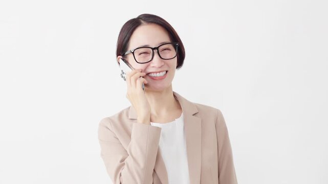 スマートフォンを使う眼鏡をかけたスーツ姿の女性