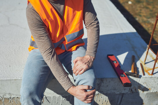 Construction worker having a accident and injured knee and leg on a construction site outdoors.