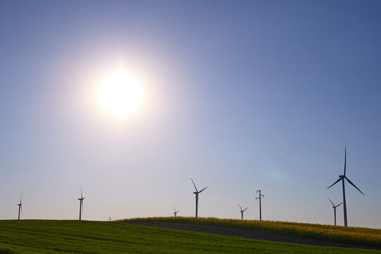 Wind turbines at sunset in green field &ndash; renewable energy, clean power, sustainable future.