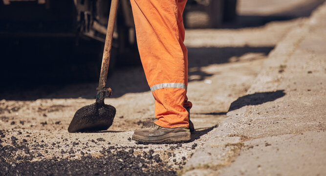 Construction worker working on a new asphalt layer on a public street.