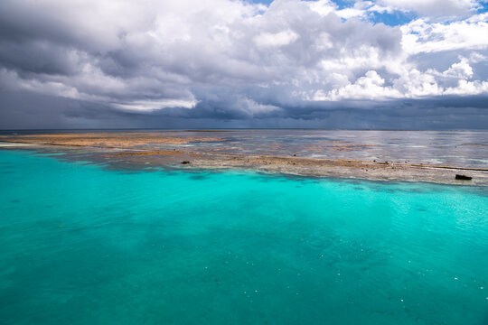 Turquoise lagoon and exposed coral reef beneath dramatic clouds at Heron Island on the southern Great Barrier Reef, Queensland, Australia.