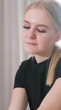 Close up shows upper part of woman wearing black clothing against light colored curtains. focus remains on their arm and partial body suggesting relaxation or treatment in calm environment