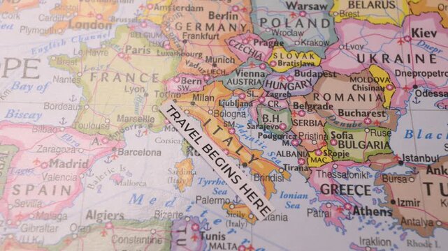 Paper Strip Travel Begins Here Placed on Map of Italy and Europe