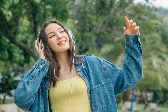 Young woman listening music while walking in the street. Travel, tourism, technology, blogging concept