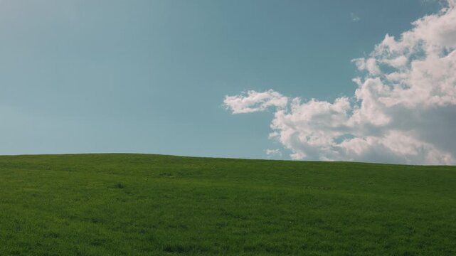 Gentle Sloping Grassland Under a Blue Sky with Clouds