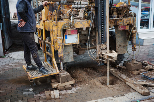 Geotechnical drilling rig operator borehole construction soil investigation hydraulic machinery during urban foundation testing and engineering work.
