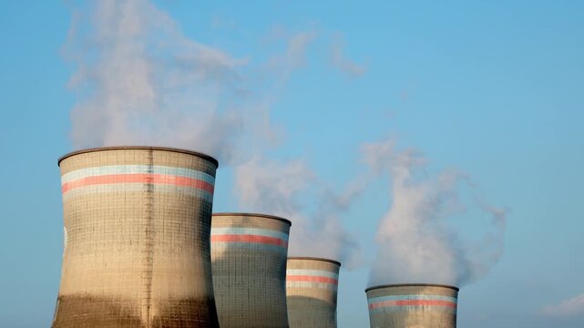 industrial cooling towers emitting steam against blue sky