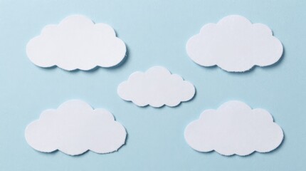 Fototapeta premium This image features paper-cut cloud shapes placed on a soft blue background, perfect for artistic designs, crafts, or creative projects that evoke a calm and dreamy atmosphere.