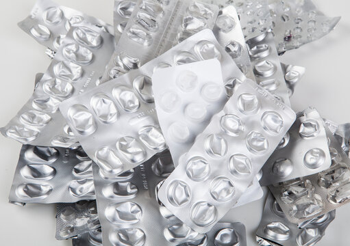 Used and empty aluminum blister packs for tablets and medications. Medical waste. Concept of empty packaging on a white background. Aluminum and plastic recycling.