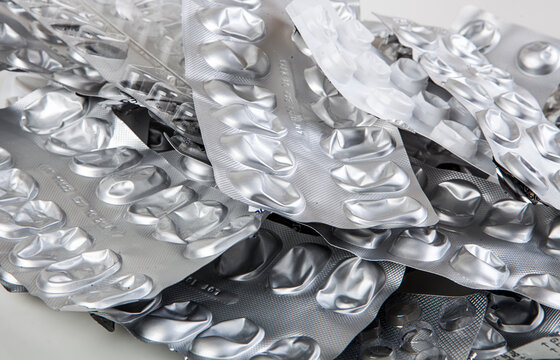 Used and empty aluminum blister packs for tablets and medications. Medical waste. Concept of empty packaging on a white background. Aluminum and plastic recycling.