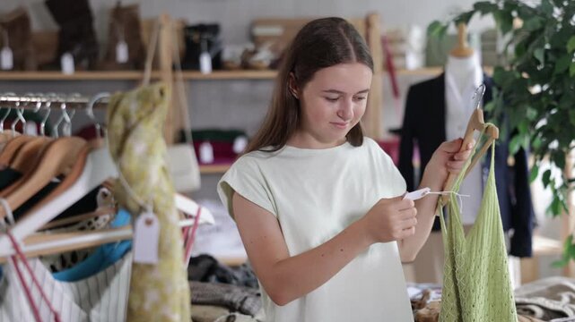 Young woman stands in a European second-hand store and chooses clothes, she supports eco-friendly fashion and reasonable consumption 