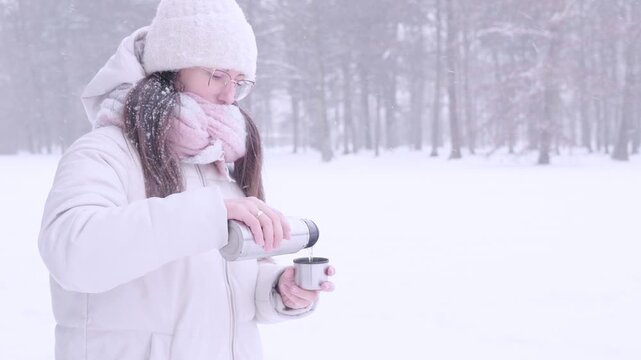 Woman outdoor break. Female serving tea during snowfall. Mindful pause concept.