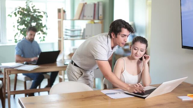 Aggressive male manager criticizing upset girl sitting at computer in workplace 