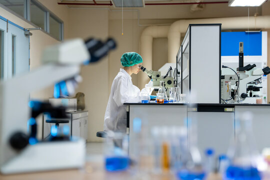 Young female researcher working in the lab, she is examining the samples under a microscope