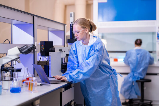 Female scientist using a microscope while conducting scientific research and analyzing samples